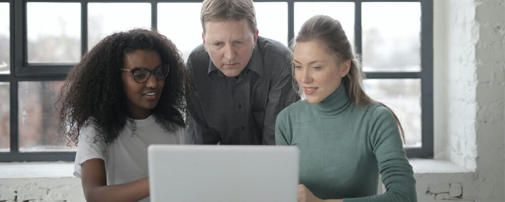 photo of three co-workers looking at a computer